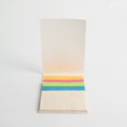 An open notebook with a set of colorful sticky tabs in orange, pink, green, and blue on the bottom page, placed against a plain white background.