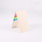 A beige triangular notepad stands upright with colorful sticky note tabs visible on one side. The tabs are pink, green, and blue, contrasting with the plain cover. The background is a plain white surface.
