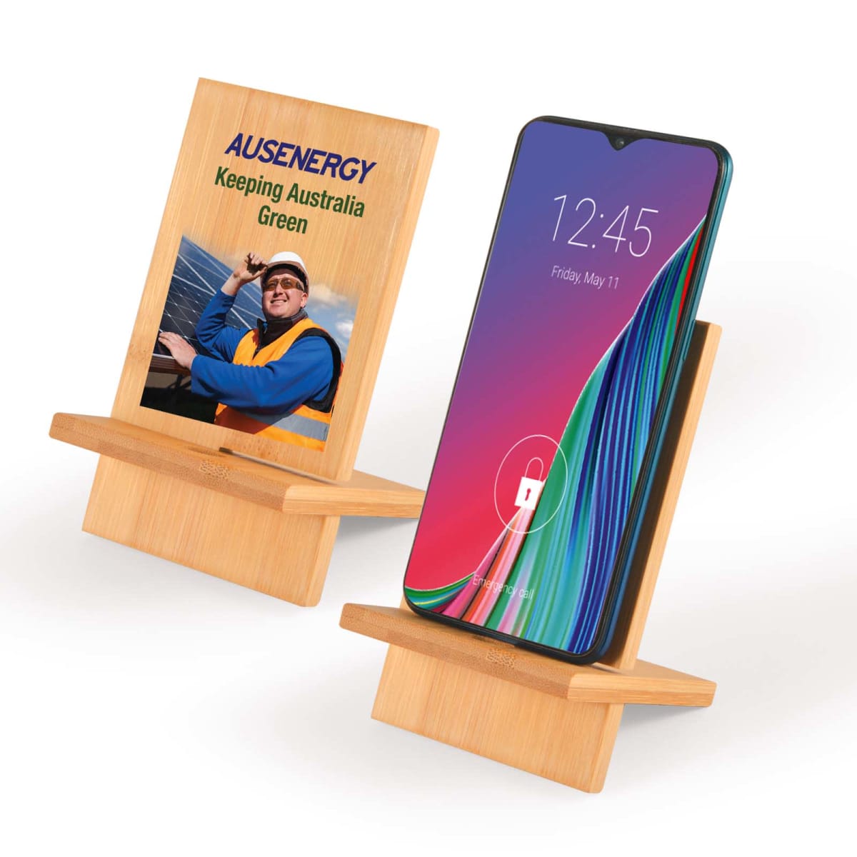 Two bamboo phone stands. The left one holds an image of a person wearing a hard hat and holding solar panels by AUSENERGY Keeping Australia Green. The right stand holds a smartphone with a colorful display showing the time 12:45 on Friday, May 11.