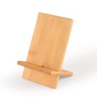 A wooden tablet or phone stand made of light-colored wood with a simple, minimalist design. It has a rectangular back support and a base with a groove for holding the device. The stand is placed on a white surface.