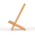 A simple wooden stand with two interlocking pieces forming a minimalist design. The lighter wood has a smooth finish, and the stand is angled slightly, possibly for holding small items or devices.