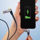 A hand holding a smartphone with a charging icon displayed on the screen. Another hand is connecting a multi-functional charging cable to the phone. The cable has a USB connector and other interchangeable connectors labeled PRO ELECTRICAL.