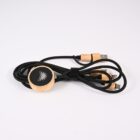 A coiled black cable with wooden accents lies against a white background. The cable features multiple connectors and a circular wooden attachment with a logo. A black Velcro strap secures it.