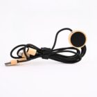 A black charging cable with wooden accents on the connectors and a circular black section, coiled neatly and secured with a Velcro strap, against a plain white background.
