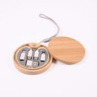 A round wooden case with a lid, containing multiple metal USB adapters arranged neatly. The case has a gray lanyard attached. The image is taken on a plain white background.