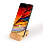 Smartphone on a wooden stand displaying a colorful abstract wallpaper with the time reading 12:45. The screen shows a lock icon, indicating it is locked.