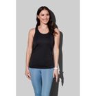 Woman in black tank top and blue leggings smiling against gray background.