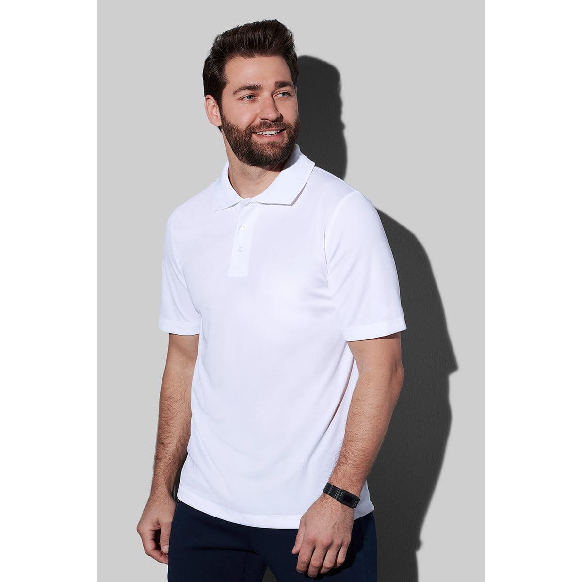 Man wearing a white polo shirt and black pants against a gray background.
