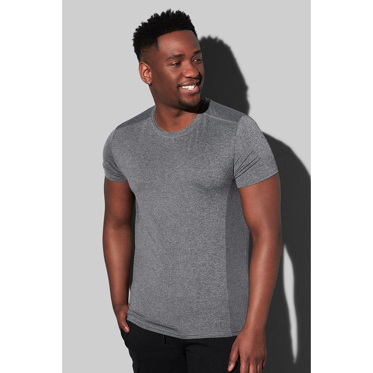 Man wearing a grey t-shirt and black pants against a light grey background.