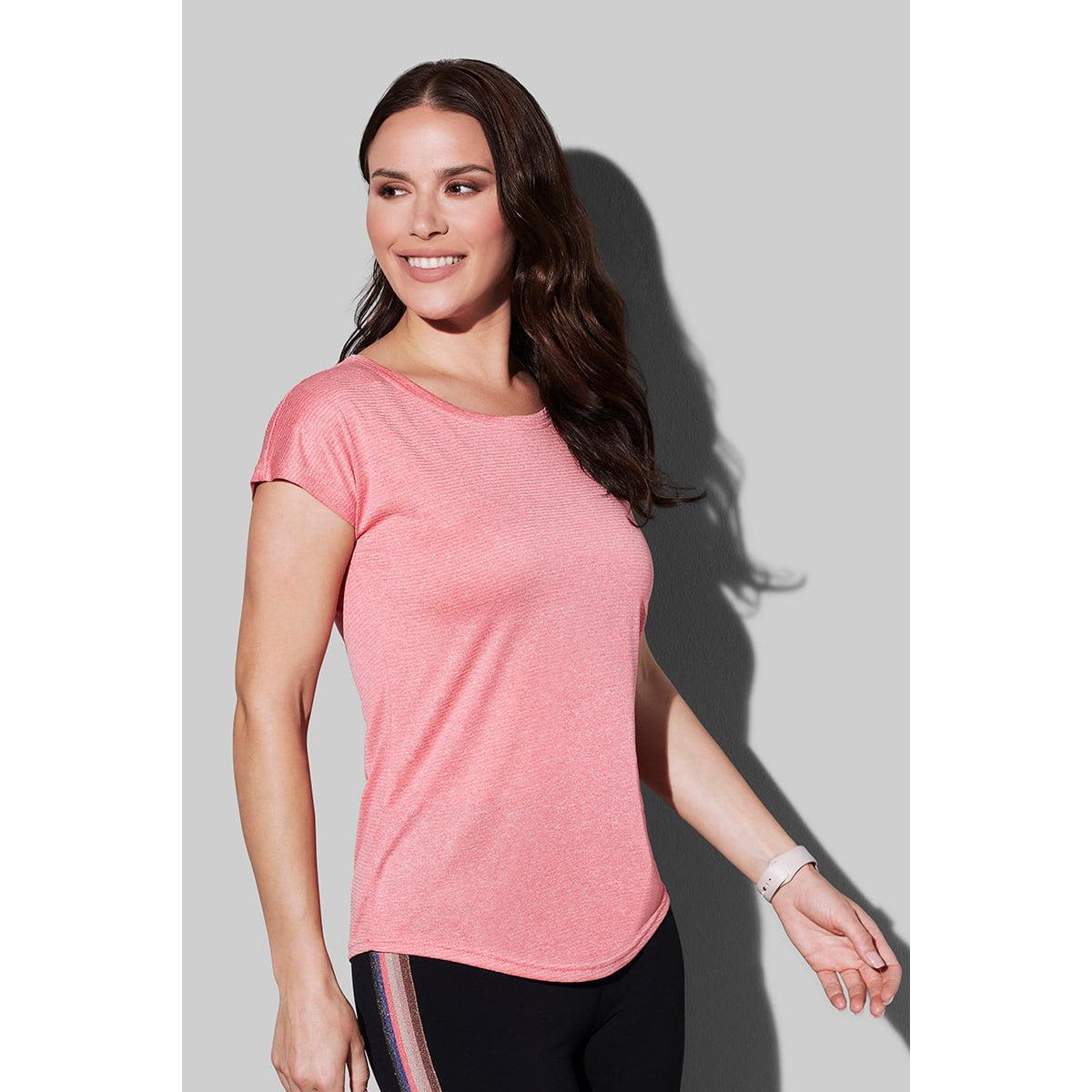 Woman in a pink shirt smiling and looking to the side against a gray background.