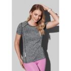 Woman in gray athletic shirt and pink leggings smiles, posing against a plain background.