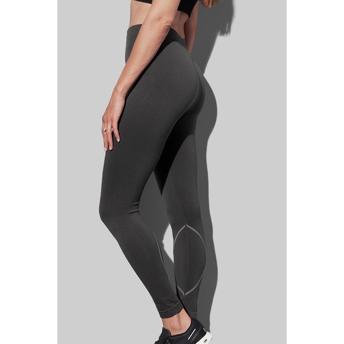 Person in dark leggings and black sneakers on a gray background.