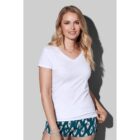 Woman in a white V-neck t-shirt and patterned shorts, smiling against a gray background.
