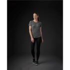 Person in activewear standing, looking left, on a dark background.