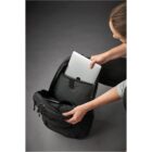 Person placing a tablet into a black backpack against a gray background.
