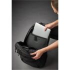 Person placing a silver laptop into a black backpack.