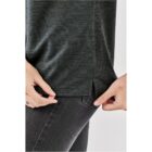 Persons hands adjust a dark green shirt over black pants.
