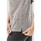 Person adjusting a light gray striped shirt with a side slit, wearing black jeans.