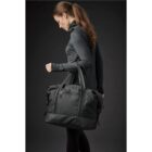 Person in a dark outfit carrying a large black duffel bag.
