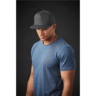 Man in a blue t-shirt and black cap against a dark background.