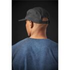 Person in a blue shirt wearing a black cap, seen from behind against a dark background.