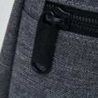 Close-up of a gray fabric backpack with a black zipper and pull tab.