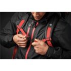Person in black jacket fastening red backpack straps.