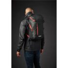 Person in black jacket with a black and red backpack, facing away against a dark background.