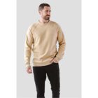 Man in a beige sweater and black pants standing against a plain gray background.