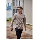 Man in sunglasses and sweatshirt walking outdoors with a camera in hand.