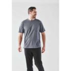 Man in a gray T-shirt and black pants stands against a plain white background.