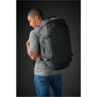 Person in a gray shirt and jeans wearing a large black backpack.