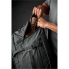 Person placing a brown bottle into a green backpack.