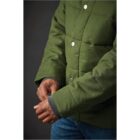 Person in green quilted jacket adjusting sleeve cuffs.