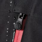 Close-up of a black zipper with red fabric underneath, partially unzipped.