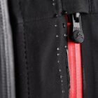 Close-up of a waterproof zipper with water droplets on a black fabric jacket.