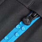 Close-up of water droplets on a blue waterproof zipper with black fabric.