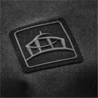 Black fabric with a stitched, abstract geometric logo patch in gray.