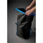 Person adjusting a black and blue waterproof roll-top backpack.