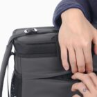 Hands opening a pocket on a black backpack.