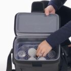 Person opening a container in a backpack, revealing organized storage.
