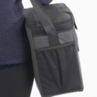 Person carrying a black insulated lunch bag with a shoulder strap.