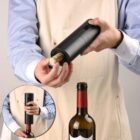 Person using an electric wine opener to remove a cork from a wine bottle.