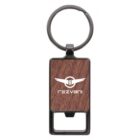 A keychain with a rectangular wooden design featuring a metal ring and a built-in bottle opener. The word Rezvani and a logo with wings are printed in white on the wooden surface.
