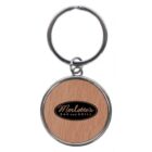 A silver metal keychain with a round wooden center featuring the text Merlottes Bar and Grill in black cursive font.