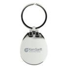 A metallic keychain with an oval-shaped pendant featuring the text Ken Garff Automotive Group and a logo. The keyring is attached at the top. The surface is reflective and polished.
