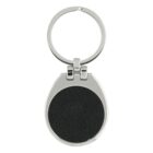 A circular keychain with a silver metal frame and loop. The center features a black textured insert. The keychain has a modern and sleek design.