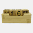 A wooden block calendar set on August 16, Monday. The blocks are arranged in a wooden holder, with two cubes showing the day and date, and long blocks for the month and day of the week. The design is minimalist and natural.