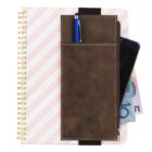 A spiral notebook with pink and white diagonal stripes is shown. A brown leather pouch attached to the notebook holds a blue pen, a smartphone, and several banknotes partially visible.