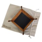 A square, brown leather valet tray with stitched edges sits on a beige drawstring bag. The trays corners are snapped upright, and the bag is partially visible with the word AGRADE printed on it.
